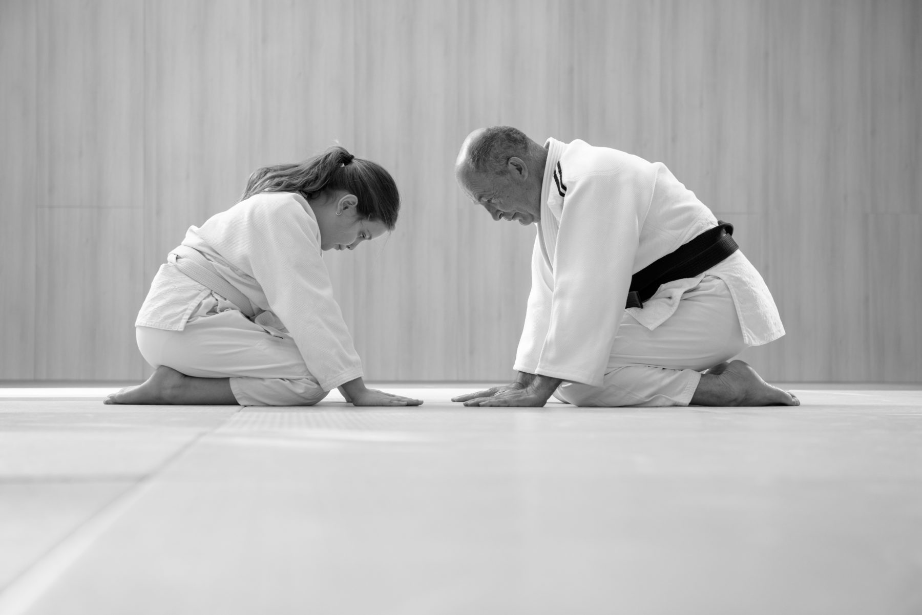 old-judo-master-and-young-female-student-kneeling-and-bowing-to-each-other